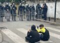 Dy fëmijë protestues ulen këmbëkryq para efektivëve