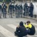 Dy fëmijë protestues ulen këmbëkryq para efektivëve